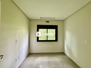 Foto de um corredor interno com paredes claras e uma janela escura.
