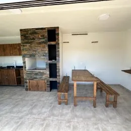 Ambiente interno com parede de pedra e mesa de madeira em espaço aberto.