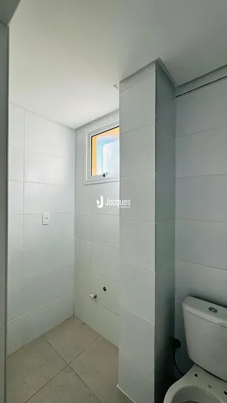 Vista de um canto interno de uma sala com paredes brancas.