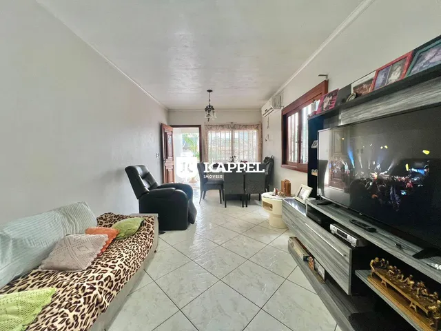 Sala de estar com sofá e televisão em um ambiente claro.
