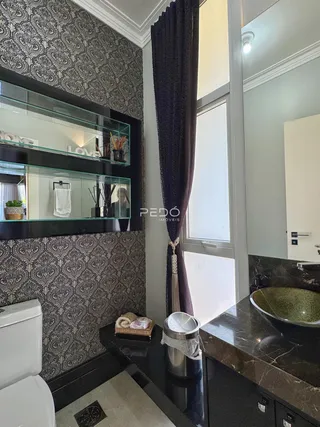 Interior de um banheiro com revestimento de parede estampado e bancada escura.