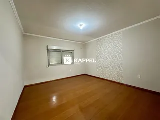 Sala de estar com piso de madeira e janela com persiana.