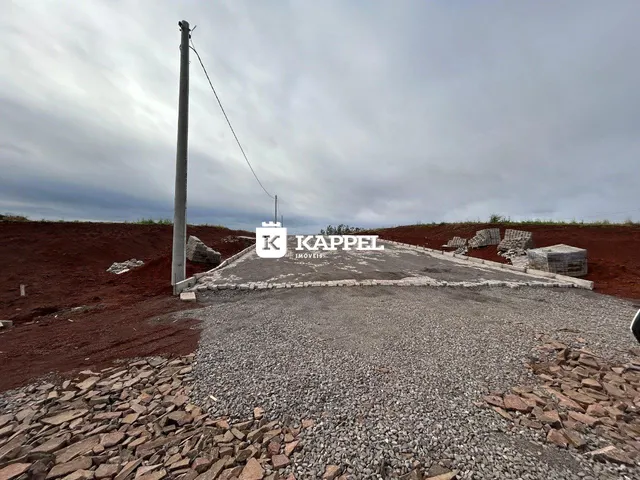 Foto da área externa de um terreno com terra vermelha e cascalho.