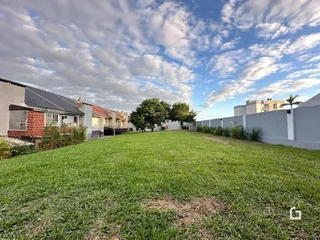 Vista externa de um jardim com gramado verde e muro de vedação.