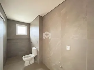 Um banheiro com paredes revestidas de cerâmica e um vaso sanitário branco.