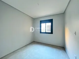 Vista interna de uma sala com paredes brancas e piso claro.