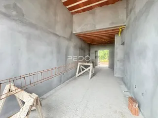 Foto de uma área interna em construção com paredes de concreto e estrutura de madeira exposta.