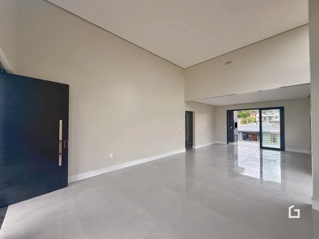 Interior de uma sala ampla com paredes claras e piso de concreto.