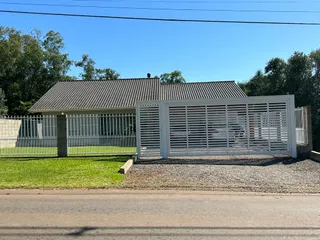 Vista da fachada de uma residência com cerca branca e gramado na frente.