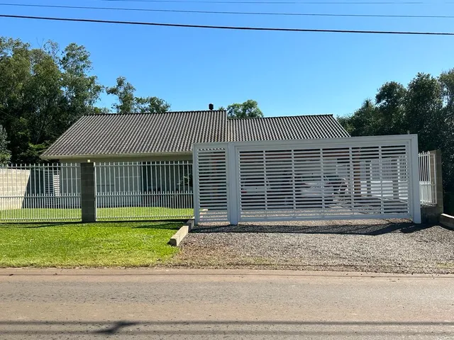 Vista da fachada de uma residência com cerca branca e gramado na frente.
