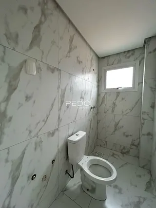 Foto de um banheiro com paredes de mármore branco e piso cerâmico.