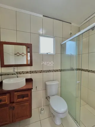 Foto interna de um banheiro com revestimento cerâmico e box de vidro.