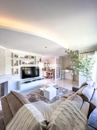 Sala de estar moderna com sofá grande e televisão em um ambiente bem iluminado.