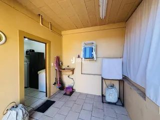 Vista de um corredor interno com parede amarela e piso de cerâmica.
