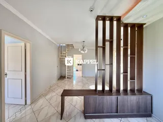 Foto do ambiente interno de uma sala com piso de cerâmica e estante de madeira.
