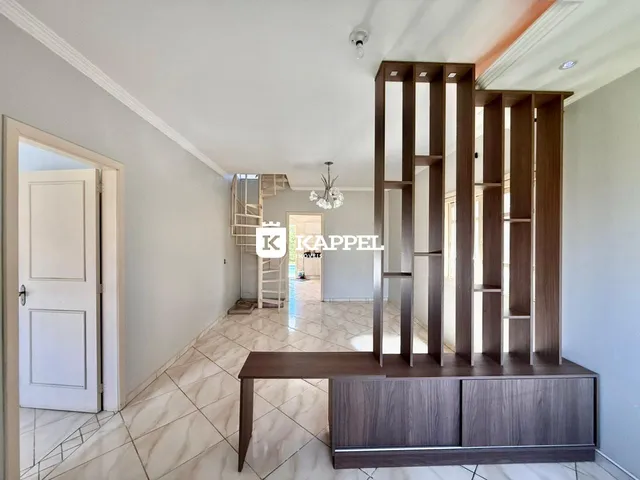 Foto do ambiente interno de uma sala com piso de cerâmica e estante de madeira.