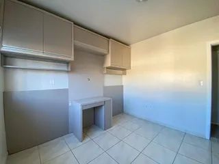 Cozinha com armários superiores e inferiores em tons neutros e piso de cerâmica clara.