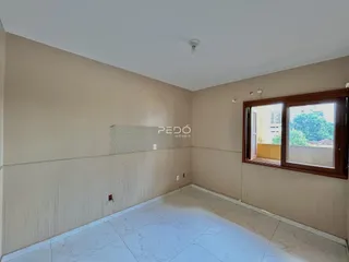 Interior de uma sala com paredes bege e piso de porcelanato claro.