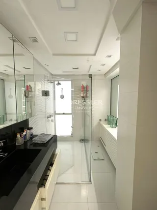 Interior moderno com revestimento branco e box de vidro.