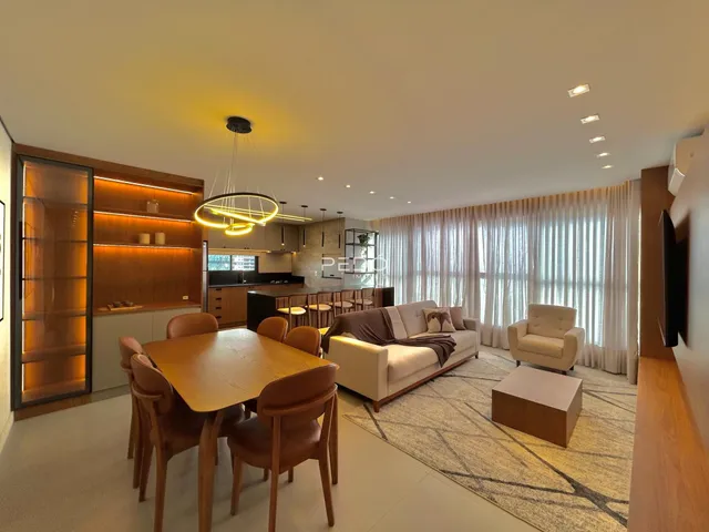 Sala de estar com mesa de jantar e grandes janelas em um imóvel no Brasil.