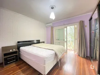 Quarto com cama e piso de madeira em um imóvel no Brasil.