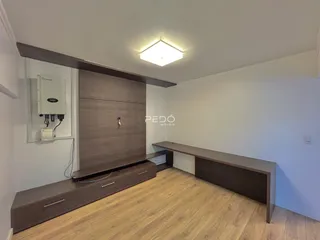Ambiente interno de uma sala com piso de madeira e móveis modernos.