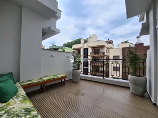 Varanda com piso de madeira e plantas decorativas.