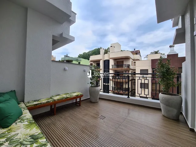 Varanda com piso de madeira e plantas decorativas.