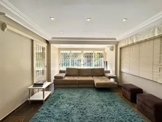 Sala de estar com um grande sofá e vista para o exterior da casa.
