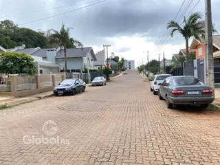Foto da rua em Lajeado, Brasil, mostrando residências e veículos estacionados.