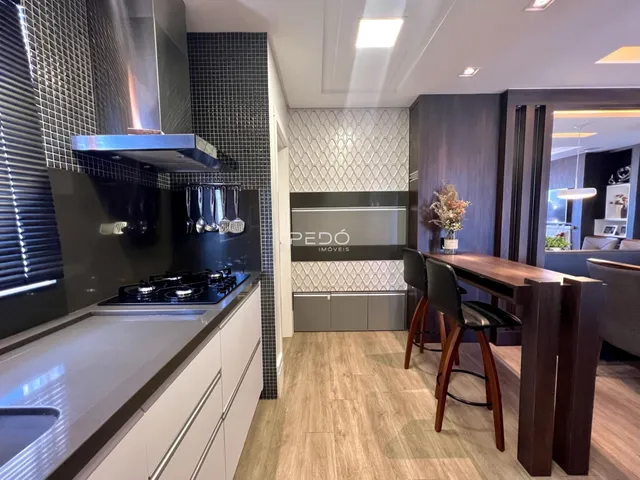 Vista da cozinha moderna com revestimento de azulejos pretos e piso de madeira clara.