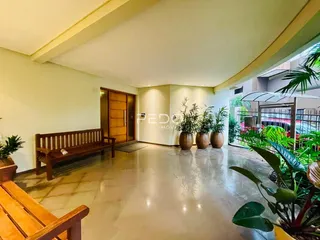 Ambiente interno de uma sala ampla com piso de cerâmica e bancos de madeira.