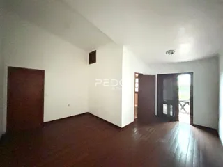 A sala apresenta piso de madeira e paredes brancas.