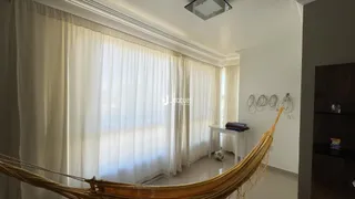 Interior de uma sala com cortinas brancas e uma rede pendurada.