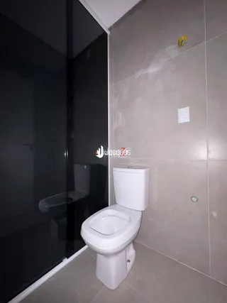 Foto interna de um banheiro com vaso sanitário e box de vidro.