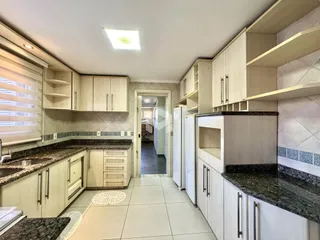 Interior da cozinha com armários e bancadas de granito.