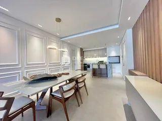 Sala de jantar moderna com mesa de madeira e cadeiras em um ambiente claro.