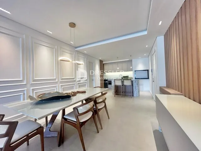 Sala de jantar moderna com mesa de madeira e cadeiras em um ambiente claro.
