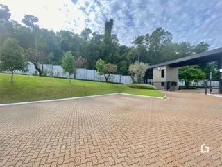 Vista externa de uma propriedade com gramado e pavimento de tijolos.