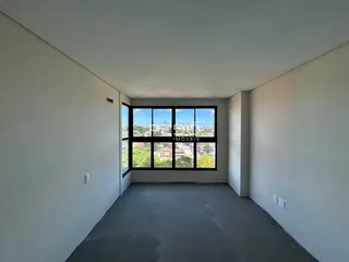 Interior de um ambiente com grande janela de vista para a cidade.