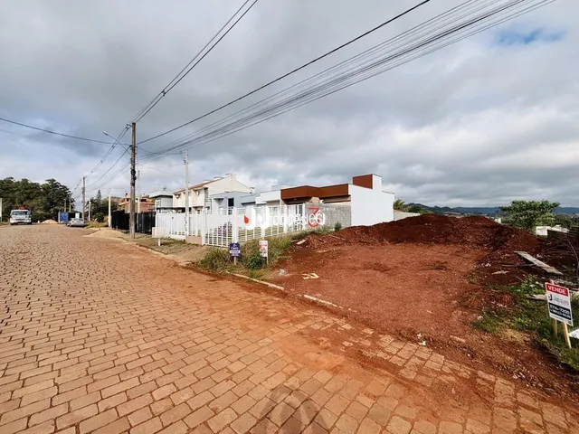 Vista externa de uma propriedade com área de terra e pavimentação no primeiro plano.