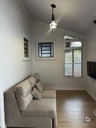 Sala de estar com paredes de tijolo branco e piso de madeira clara.