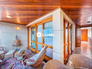 Sala de estar com forro de madeira e móveis de vime.