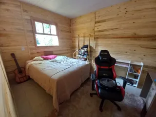 Quarto com paredes de madeira e cama grande.
