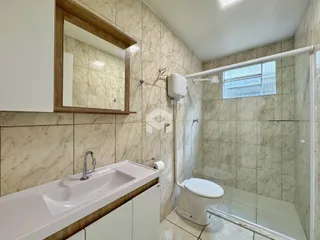 Banheiro com piso de cerâmica e box de vidro.