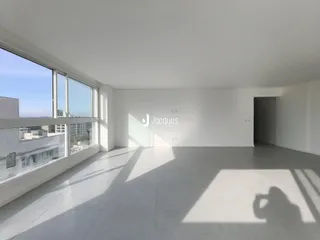 Interior de uma sala de estar com grandes janelas e piso claro.