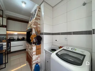 Interior de uma cozinha com parede de tijolos expostos e armários brancos.