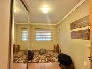 Vista interna de uma sala com piso de madeira e tapete.