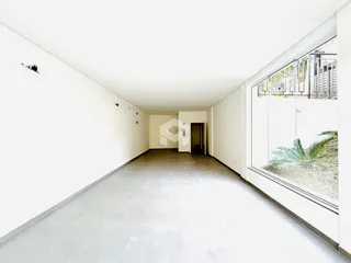 Hall de entrada longo com paredes brancas e piso claro.