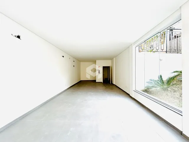 Hall de entrada longo com paredes brancas e piso claro.